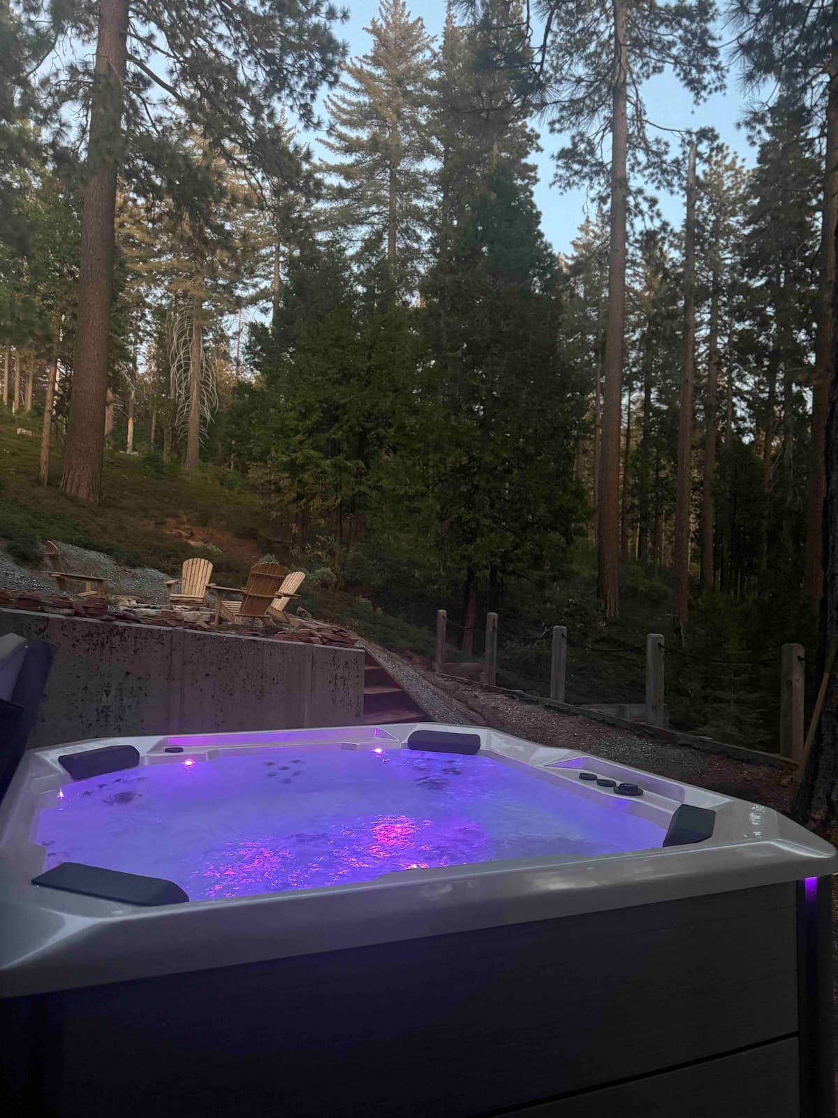 Hot tub glowing at dusk under the pines